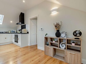 A modern kitchen with white cabinetry, a black range hood, and a wooden floor. - 1 Bed in Bakewell (oc-91367) (Youlgreave)
