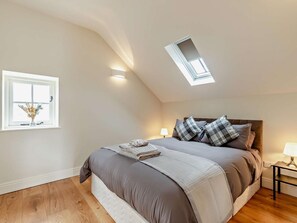 A bedroom with a skylight, a window with flowers, a bed with a blanket, and a bedside table with a lamp. - 1 Bed in Bakewell (oc-91367) (Youlgreave)