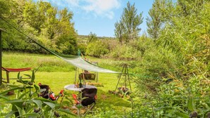 Un'area pranzo all'aperto con tavolo e sedie, immersa nel verde e tra alberi.