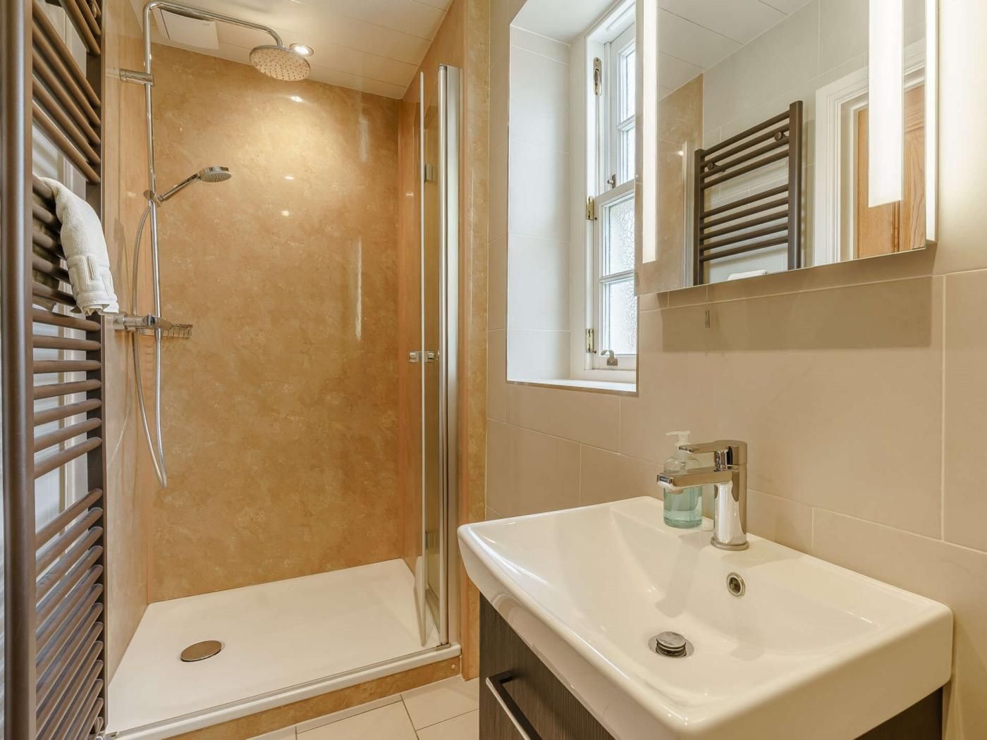 A bathroom with a glass-enclosed shower, a white sink, and a mirror above the sink.