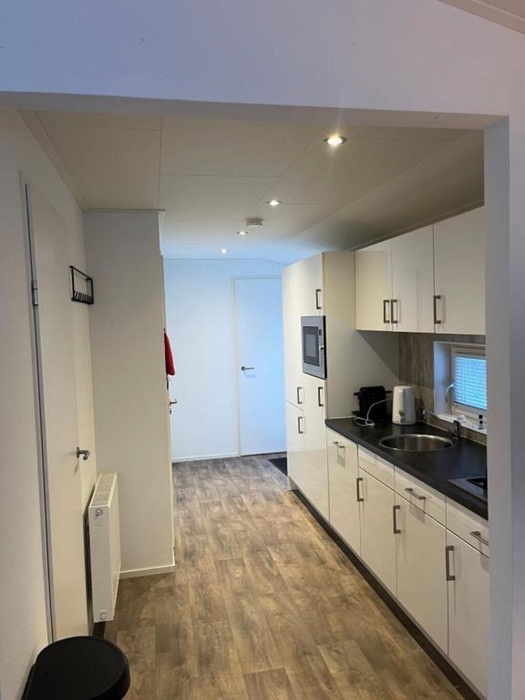 A modern kitchen with white cabinets, a black countertop, and a built-in microwave.
