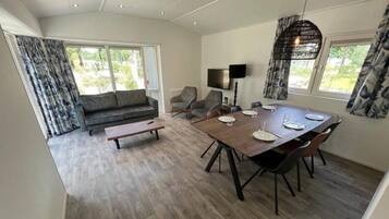 Een eethoek met een houten tafel en stoelen, een bank en een televisie.