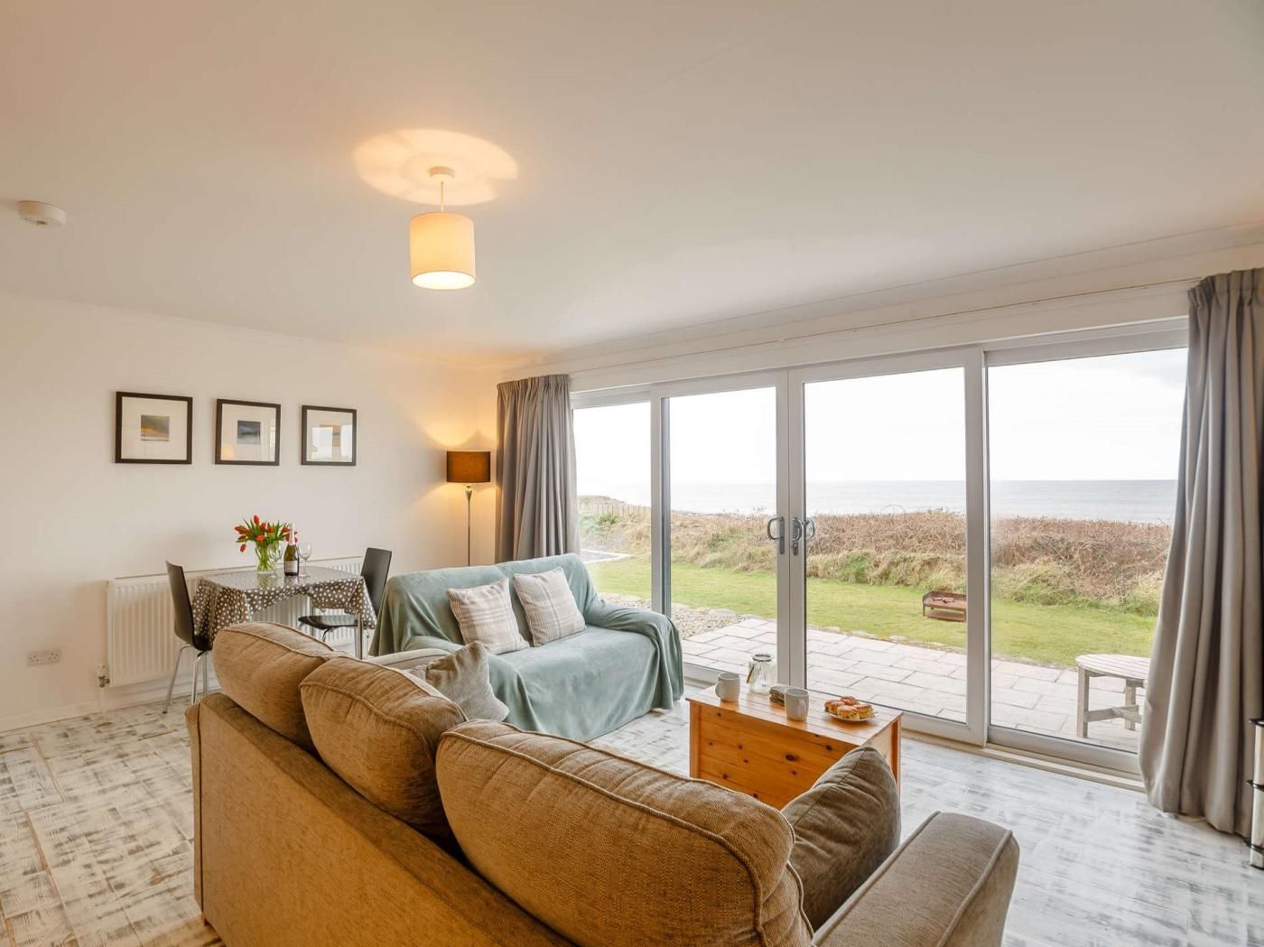 Un salon avec un canapé, une table basse et une vue sur la mer, visible à travers de grandes portes vitrées.