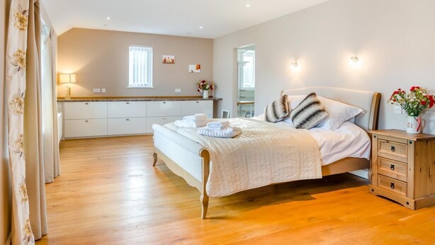 A bedroom with a bed, bedside table, wooden dresser, and a bathroom visible through an open door. - 5 Bed in Brecon (oc-90660) (Lower Chapel)