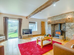 A living room with a stone fireplace, a television, and a red rug. - 5 Bed in Brecon (oc-90660) (Lower Chapel)