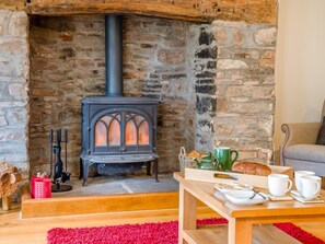 A cozy room with a stone fireplace, a wooden table with breakfast items, and a comfortable seating area. - 5 Bed in Brecon (oc-90660) (Lower Chapel)