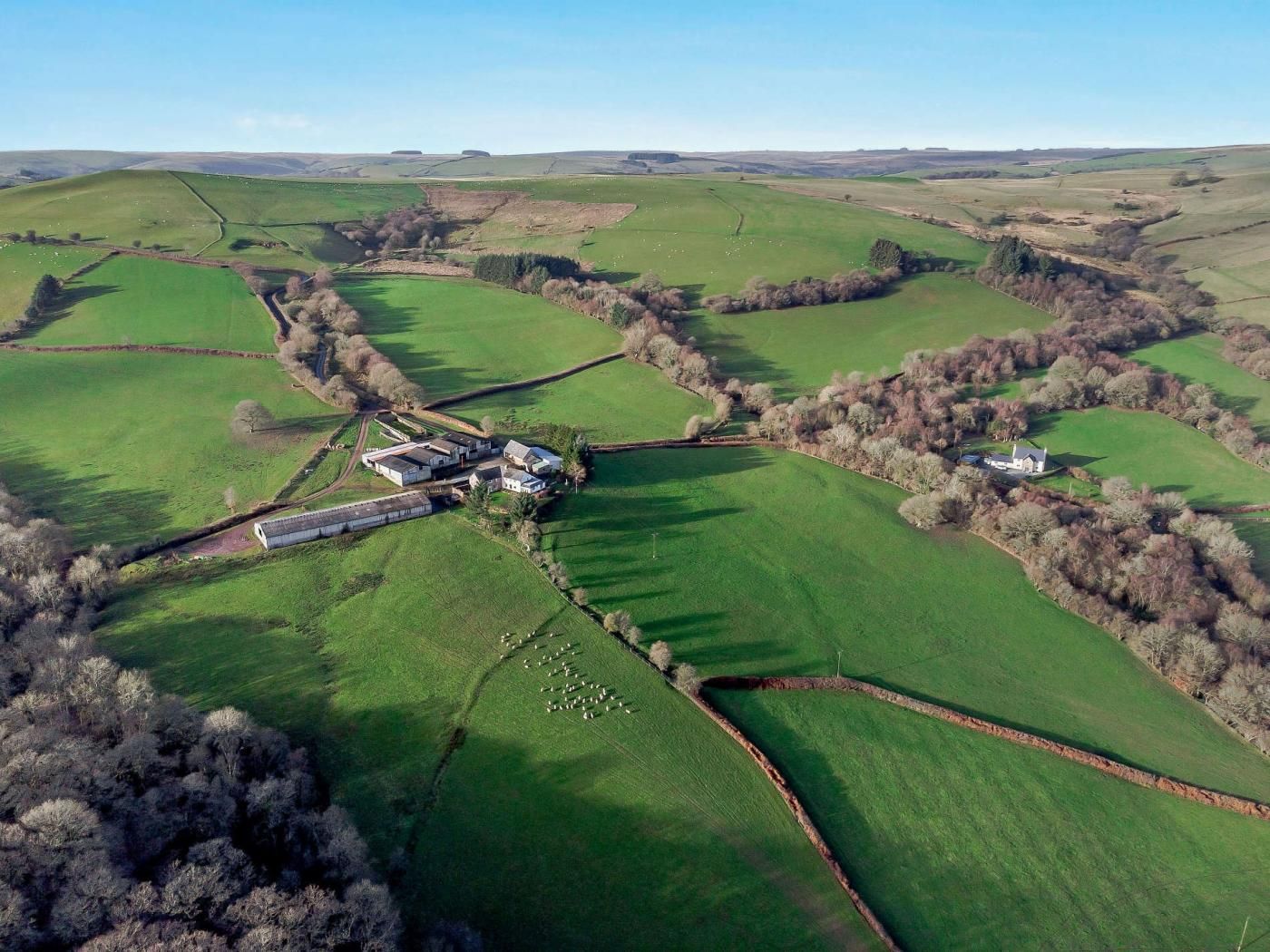 An aerial view of a rural property with fields, a farmhouse, and a barn.