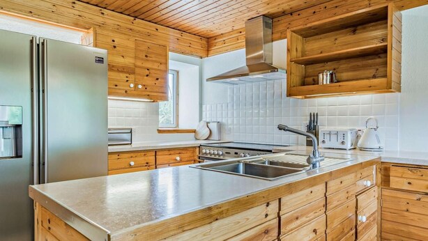 A modern kitchen with wooden cabinetry, a stainless steel refrigerator, a built-in oven, and a large island with a sink. - 5 Bed in Dunkeld (oc-90585) (Dunkeld)