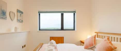 A bedroom with a bed, pillows, a bedside table, a window, and wall art.