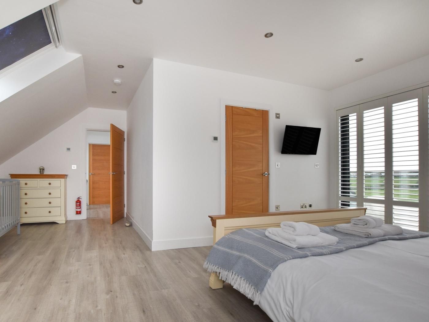 A bedroom with a bed, a TV, a wardrobe, and a bathroom.