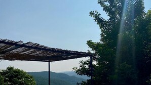 A swimming pool with a pergola overhead, surrounded by lush greenery and a mountainous backdrop. - Old stone sheepfold: charm and authenticity in the heart of nature. Dog, okay. (Saint-Beauzély)