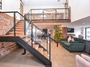 A modern interior with a staircase, a Christmas tree, and a green sofa.