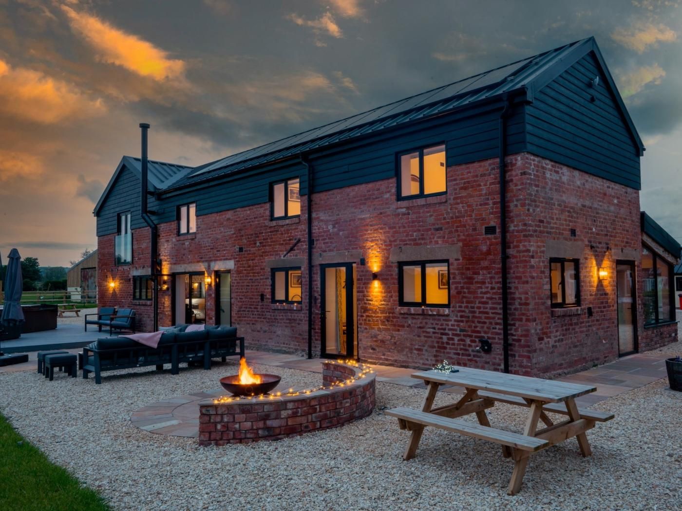A brick building with a fire pit and picnic table in the foreground.