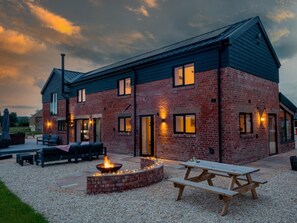 A brick building with a fire pit and picnic table in the foreground.
