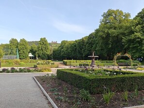 Ein Park mit einem Brunnen, ordentlich geschnittenen Hecken und einem Kiosk.