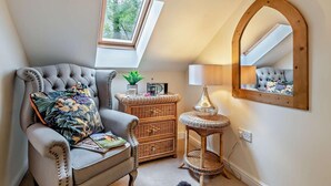 A loft bedroom with a tufted armchair, a wicker side table, a mirror, and a skylight. - 3 Bed in Matlock (oc-90663) (Matlock)