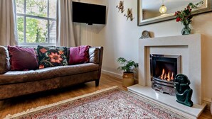 A living room with a sofa, fireplace, TV, and a large window. - 3 Bed in Matlock (oc-90663) (Matlock)
