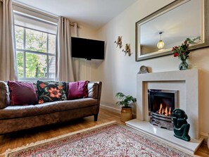 Ein Wohnzimmer mit einer Couch, Kamin, Fernseher und einem großen Fenster.