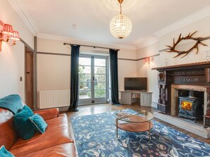 Ein Wohnzimmer mit Sofa, Kamin, Fernseher und einer Kristallleuchter.