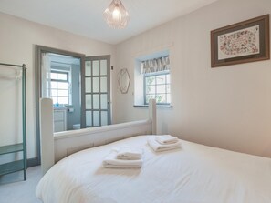 Ein Schlafzimmer mit einem Bett, einem Fenster, einer Tür und einem gerahmten Bild an der Wand.