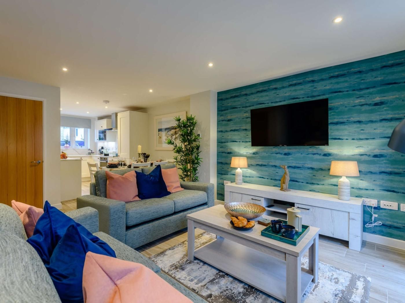 A modern living room with a grey sofa, a coffee table, and a wall-mounted TV.