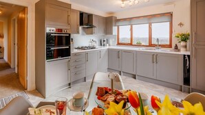 A modern kitchen with grey cabinets, a built-in oven, and a large window. - 1 Bed in Northwich (oc-91266) (Foxwist Green)