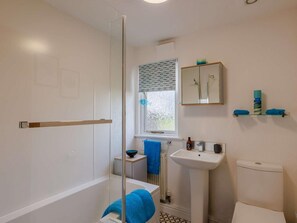 A bathroom with a bathtub, a sink, a toilet, a window with a patterned curtain, and a mirror above the sink. - 1 Bed in Northwich (oc-91266) (Foxwist Green)
