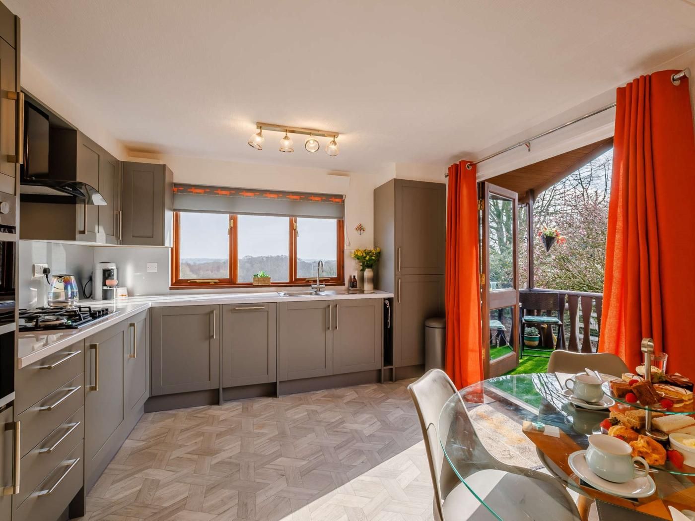 A modern kitchen with a large window, a dining area with a glass table, and a view of the outdoors.