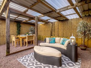 A covered outdoor seating area with a table and chairs, a sofa with cushions, and a potted plant. - 1 Bed in Northwich (oc-91266) (Foxwist Green)