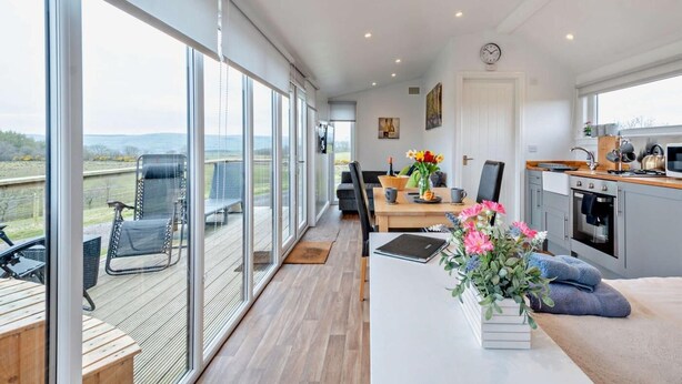 A spacious room with a large sliding glass door leading to an outdoor area, a dining table with chairs, a kitchen area, and a sofa with a view. - 1 Bed in Dalry (oc-91418) (Dalry)
