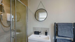 A bathroom with a glass shower enclosure, a white sink with a black soap dispenser, and two towels on a towel rack. - 1 Bed in Barnstaple (oc-91387) (Prixford)