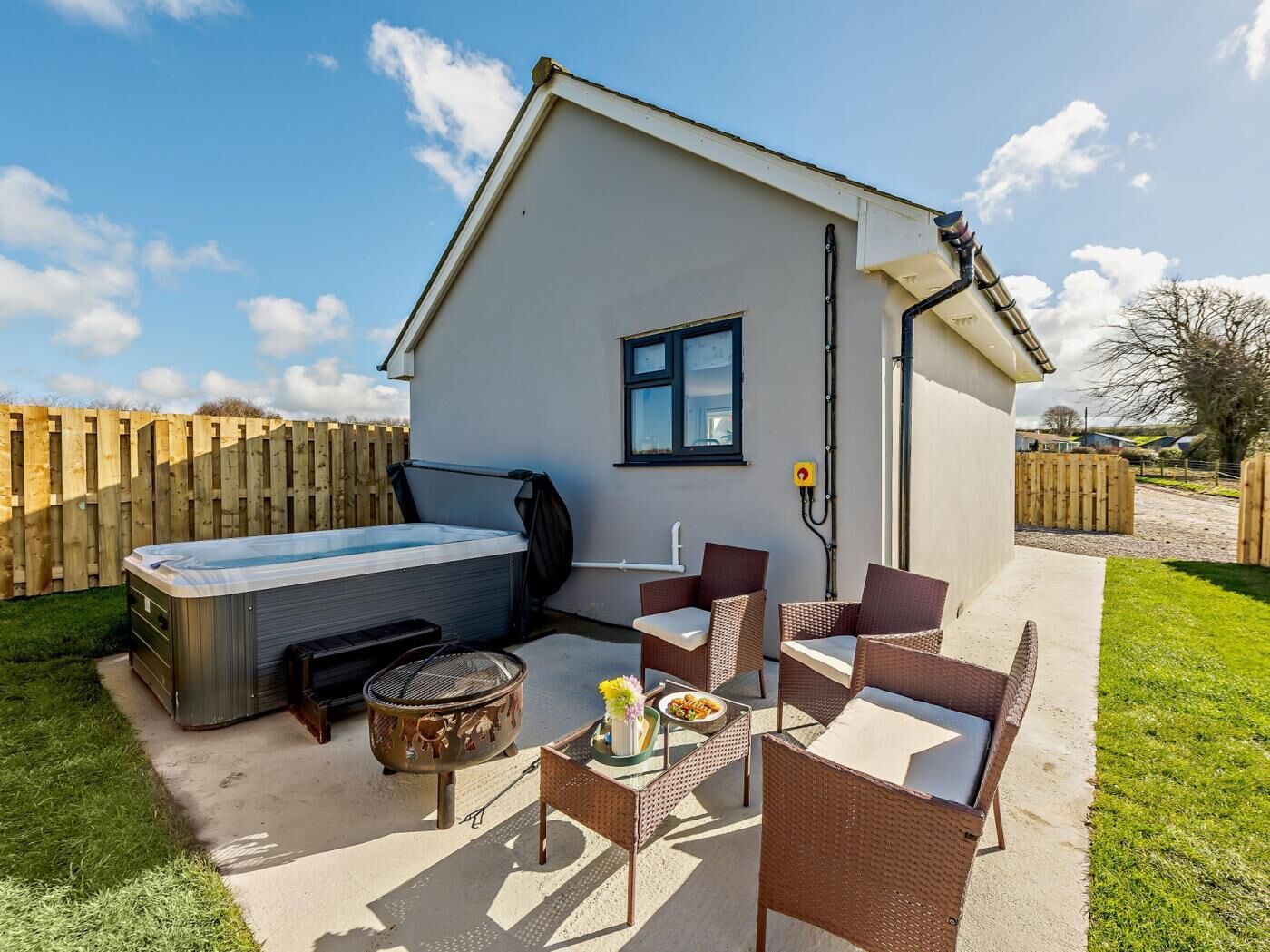 Een klein, laag gebouw met een hottub, terras en vuurkorf.