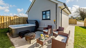 A small, single-story building with a hot tub, outdoor seating, and a fire pit. - 1 Bed in Barnstaple (oc-91387) (Prixford)