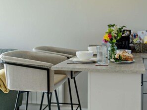 A dining area with a table set for two, including a white bowl, a glass, and a plate with bread. - 1 Bed in Barnstaple (oc-91387) (Prixford)