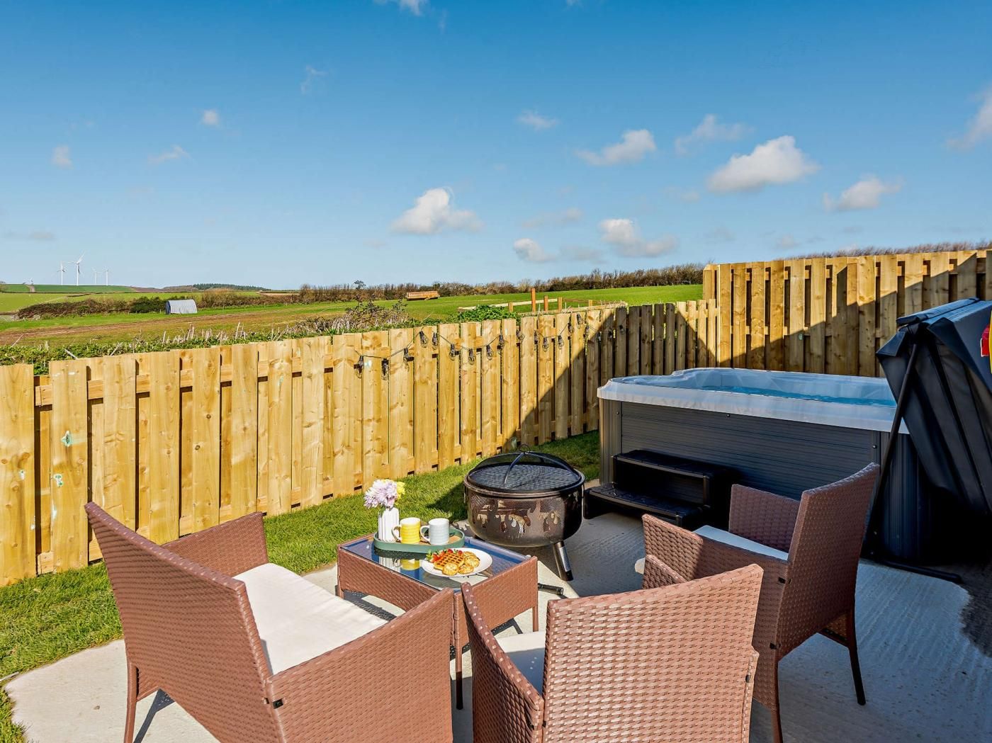 An outdoor patio with wicker furniture, a hot tub, and a grill.