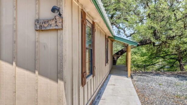 A building with a sign reading 'River Bluff,' a covered porch, and a gravel ground. - Riverfront Cabins  and  Vacation Homes (Rio Frio)