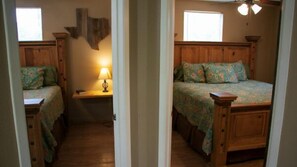 Ein Schlafzimmer mit zwei Holzbett, einem Nachttisch, einer Lampe und einem Fenster.