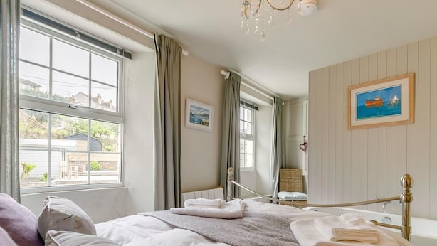 Ein Schlafzimmer mit Bett, Fenster, einem Bild an der Wand und einem Kronleuchter.