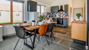 A modern kitchen with a dining area, a TV mounted above the counter, and a view of the outside. - 3 Bed in King's Lynn (oc-91286) (North Runcton)