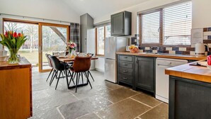 A modern kitchen with a dining area, large windows, and a view of the outdoors. - 3 Bed in King's Lynn (oc-91286) (North Runcton)