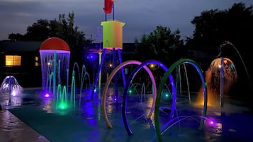 An outdoor water feature with multiple fountains and illuminated structures.