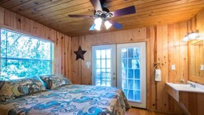 Quarto com cama, ventilador de teto, janela e porta.