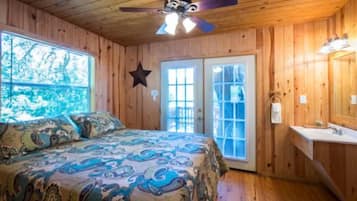 A room with a bed, a ceiling fan, a window, and a door.