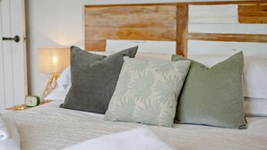 A bed with pillows, a bedside lamp, and a clock on a nightstand.