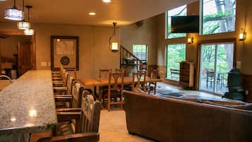 A kitchen with a granite countertop, wooden chairs, a wooden dining table, and a stone fireplace.
