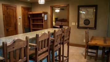 A kitchen with a granite countertop, wooden chairs, and a dining table.
