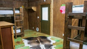 A room with bunk beds, a ladder, a door, and a colorful floor. - Riverfront Cabins  and  Vacation Homes (Rio Frio)