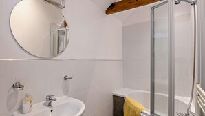 Een badkamer met een witte wastafel, spiegel en douche.