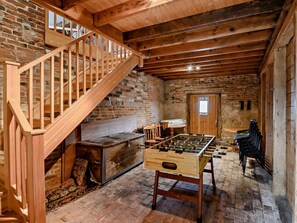Una habitación acogedora con una escalera de madera, una mesa de fútbol de mesa y una chimenea.