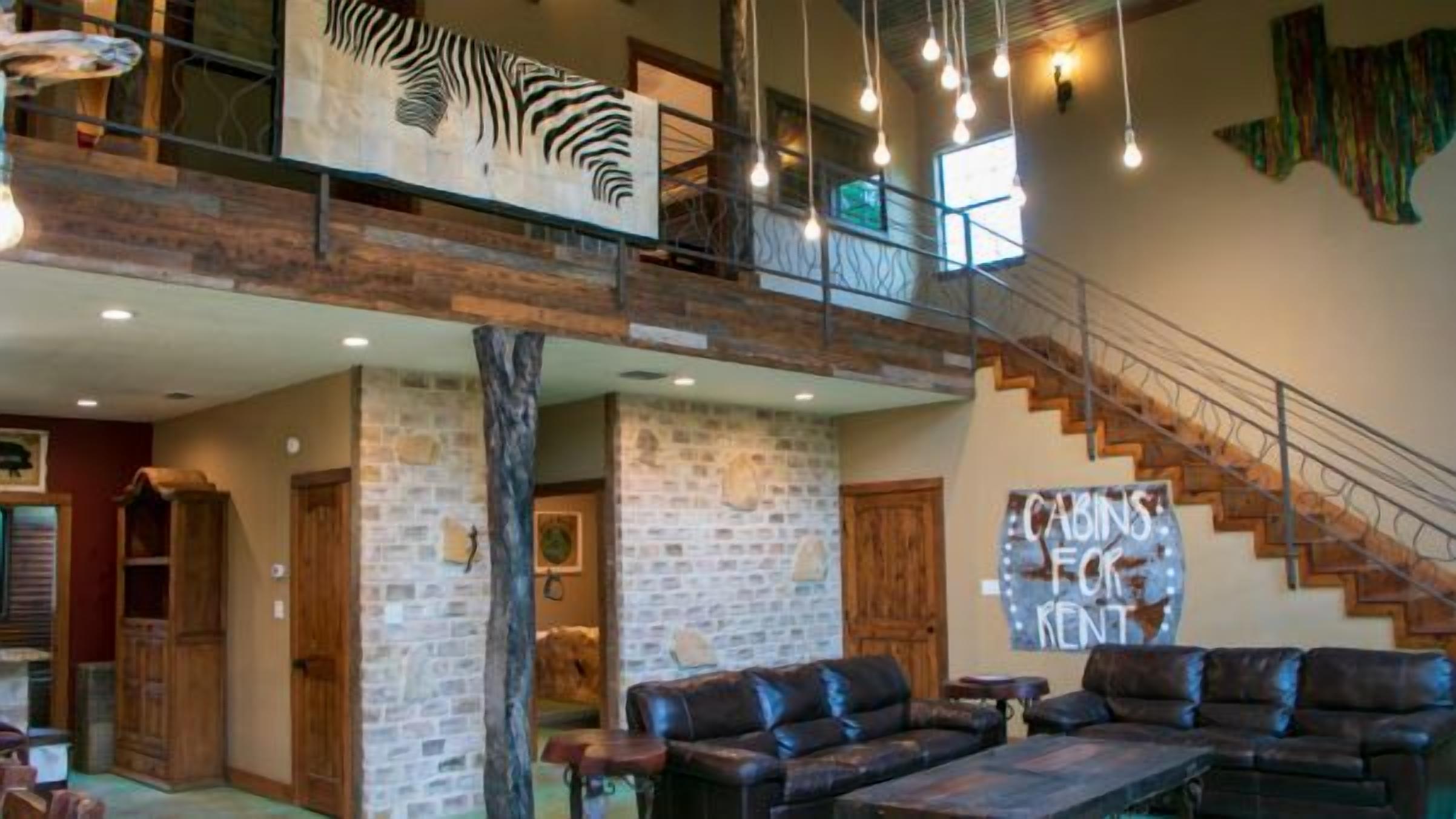 A spacious interior with a high ceiling, a staircase, leather seating, and a zebra artwork.